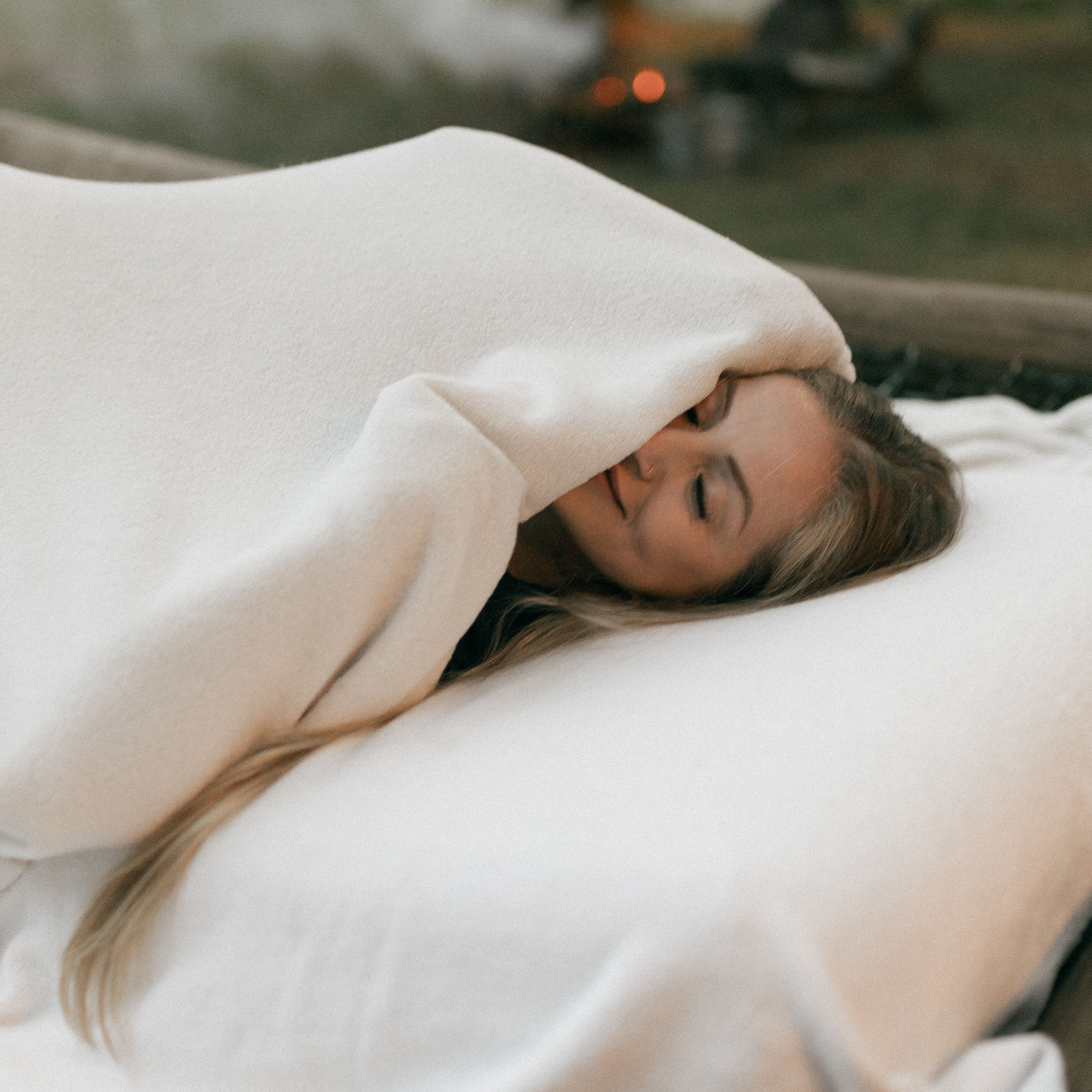 Person relaxing in bed under a blanket, representing the calming nighttime effects of THC gummies for sleep and relaxation.