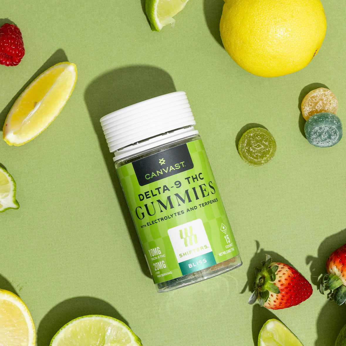 Canvast Bliss Delta-9 THC gummies with CBD on green background surrounded by lemon, lime, and fruit slices