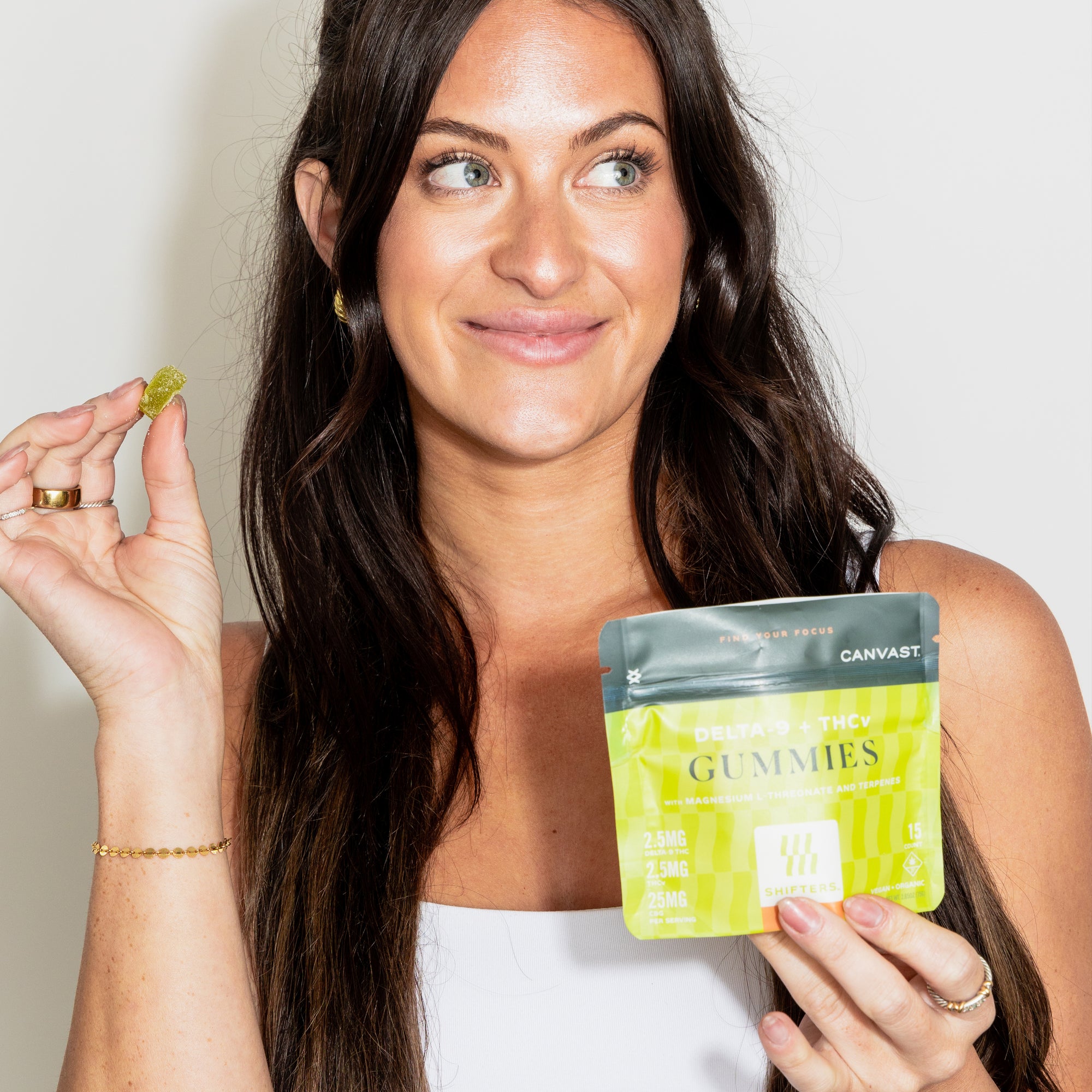 Woman holding a gummy and a bag of Shifters™ Focus Gummies with THCv + Delta-9 THC and terpenes