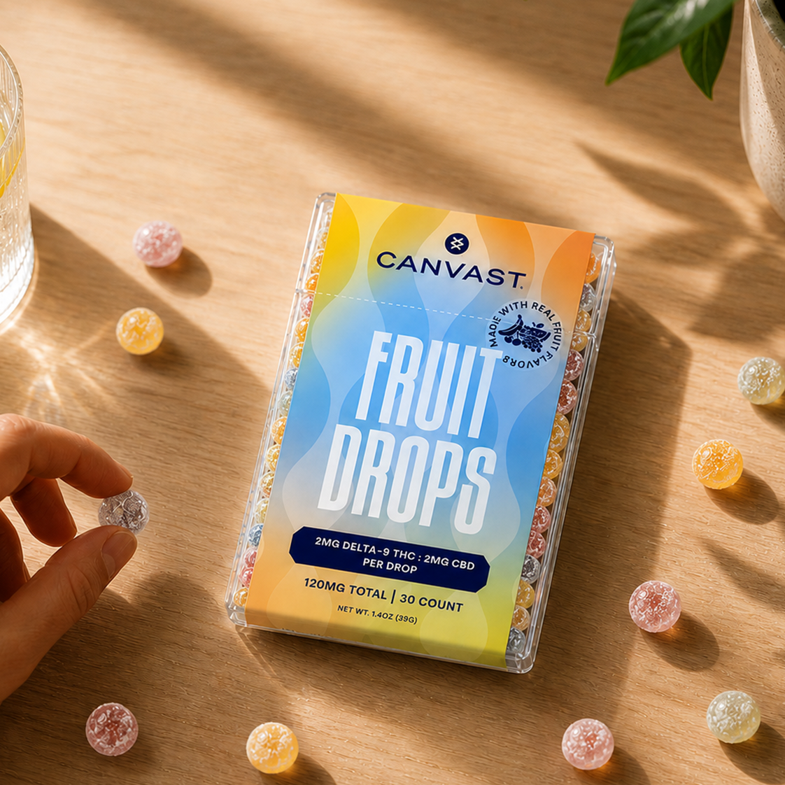 Canvast Fast-acting Sublingual Fruit Drops packaging on a wooden surface with colorful drops scattered around