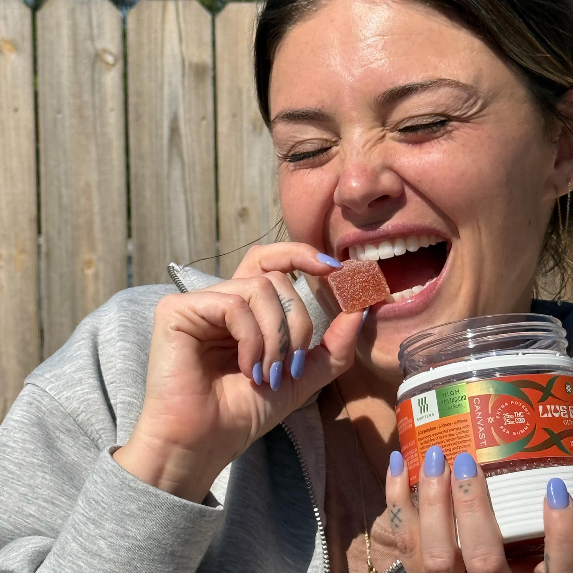 Person holding and eating a High-dose THC gummy outdoors, illustrating what THC gummies feel like and the edible cannabis experience.
