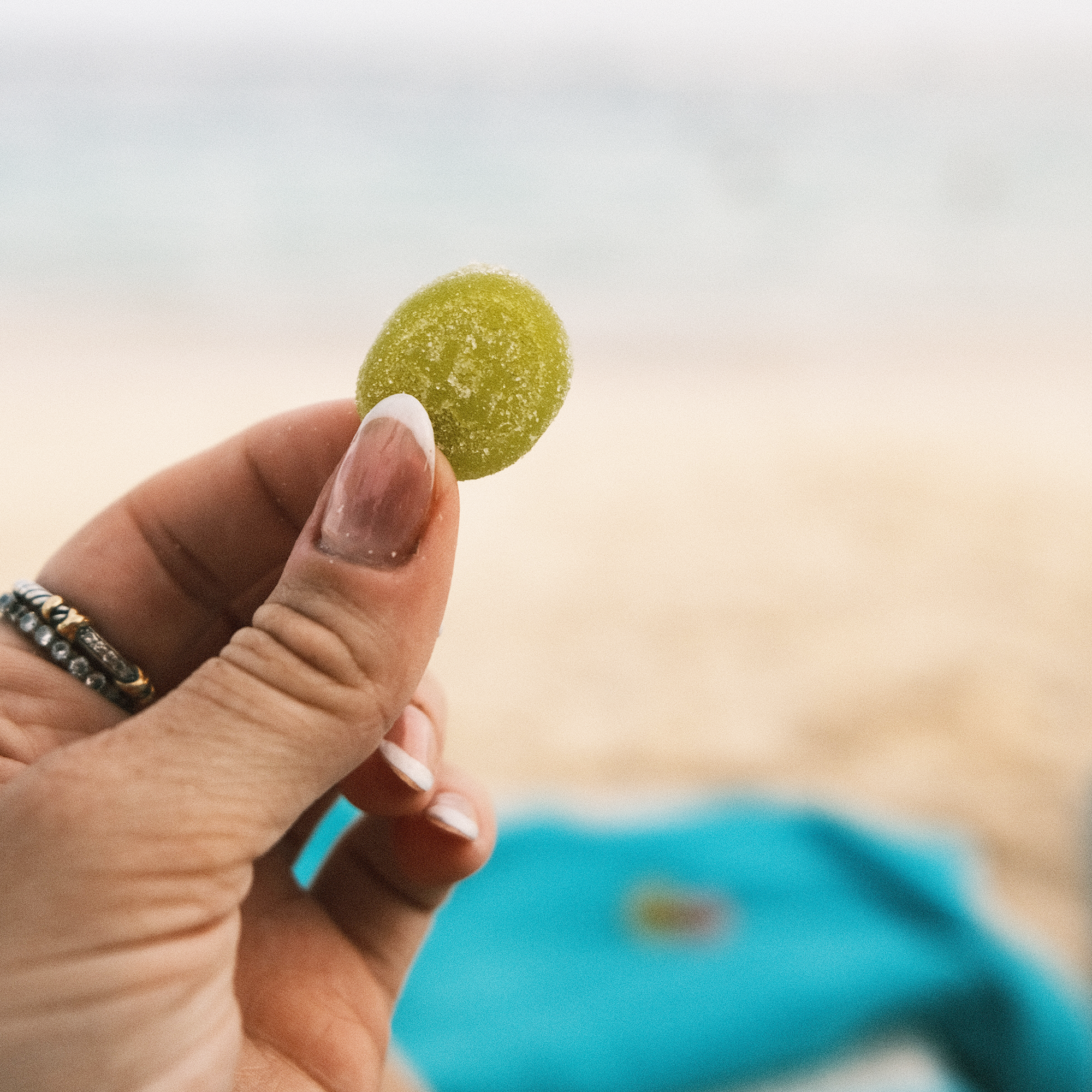 Woman holding THC gummy on the beach