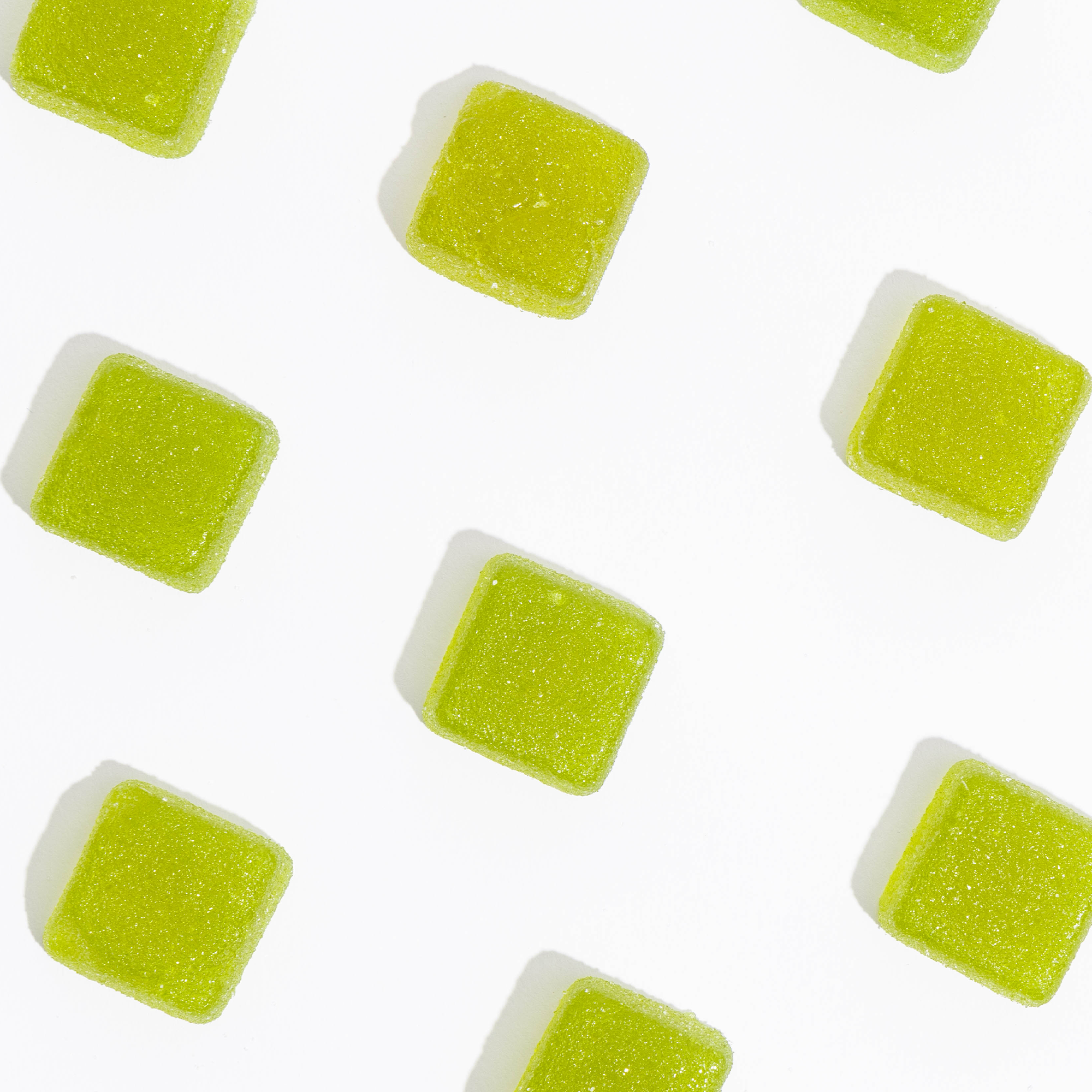 High dose live rosin gummies scattered on a white background