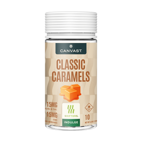 A bottle of Canvast Classic Caramels CBD edibles, featuring a beige label with brown text, an illustration of two caramel cubes, and a white ribbed cap, set against a plain white background.